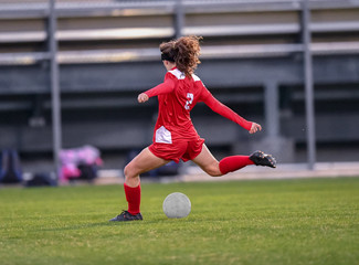 young high school girl competing in a soccer match