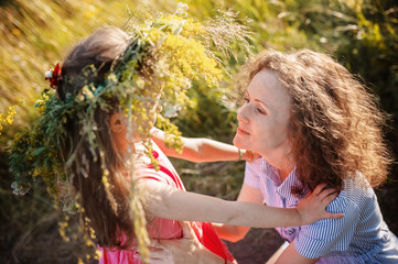 Mom hugs little daughter in nature in summer