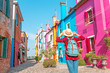 Happy asian traveler woman having fun on well known Burano island near Venice. Travel and vacation in Italy concept