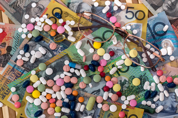 Wall Mural - Spectacles with colorful pills on australian dollars