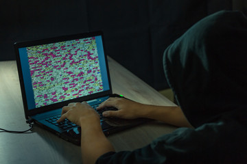 dangerous hooded hacker on laptop breaks internet code and spread virus on a computer systems