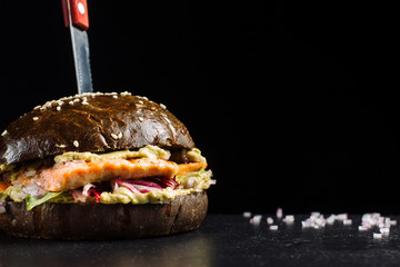 Delicious salmon burger, black dough buns sprinkled with sesame.