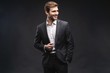 © opolja - Portrait of a handsome young businessman dressed in suit isolated over gray background.