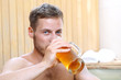 Picie piwa. Przystojny mężczyzna zażywa kąpieli w bali z woda termalną pijąc piwo kuflowe.