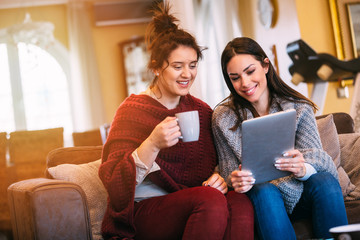 Wall Mural - Two female friends watching movie on laptop at home