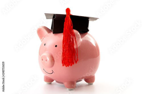 College education costs, tuition financial aid, university graduate economic cost concept theme with close up on piggy bank wearing a graduation cap isolated on white background