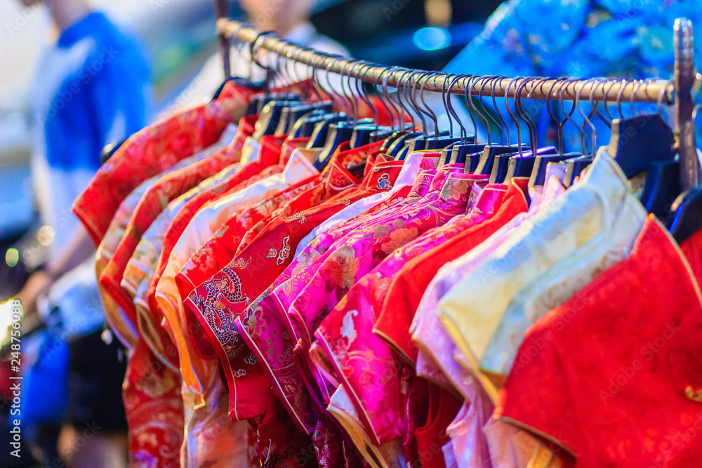 Beautiful Qipao (cheongsam dress or Chinese dress) for women hanging on a  clothes line in night market for sale to customers during the festival is Chinese  New Year at Bangkok, Thailand. Stock