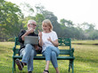 © xreflex - Senior man and woman couple connected on laptop computer in a park on a sunny day. relax in the forest spring summer time. free time, lifestyle retirement grandparents concept.