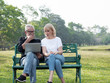 © xreflex - Senior man and woman couple connected on laptop computer in a park on a sunny day. relax in the forest spring summer time. free time, lifestyle retirement grandparents concept.