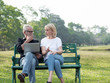 © xreflex - Senior man and woman couple connected on laptop computer in a park on a sunny day. relax in the forest spring summer time. free time, lifestyle retirement grandparents concept.