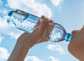  Female drinking bottle of water on a hot summer day.