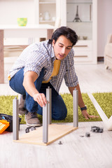 Young handsome man repairing chair at home