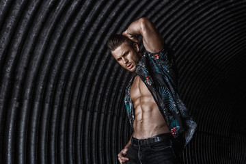 Wall Mural - Muscular young man with beard on dark tunnel urban background. Fashion portrait of brutal strong muscle guy with modern trendy hairstyle. Model, fashion concept. Sexy naked torso, six pack abs.