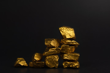 A pile of gold nuggets or gold ore on black background, precious stone or lump of golden stone, financial and business concept.