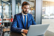 © Dusan Petkovic - Bearded businessman in formal wear with serious facial expression using laptop while sitting in cafeteria next to window.