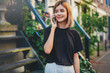 © makarovada - Happy smiling teenage girl calling to her friends using mobile phone and walking around the city streets, staying connected in every part of the world without limit, flare light and space for logo