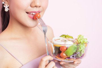 Beautiful Healthy young woman eating salad  on pink  background