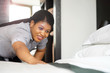 © polack - Maid making bed in hotel room. Staff Maid Making Bed. African housekeeper making bed. Toning