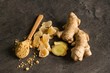 Ginger root, candied and ginger powder in wooden spoon over grey concrete background