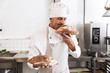 © Drobot Dean - Image of handsome male baker in white uniform standing at bakery, and holding bread