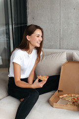 Wall Mural - Happy young teenage girl eating pizza on a couch