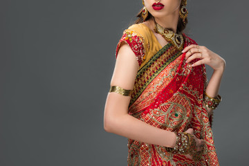 cropped view of indian woman posing in traditional sari and accessories, isolated on grey