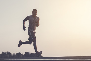 Wall Mural - young man runner running on running road in city park