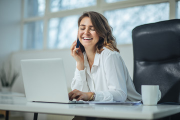 Young woman in office talking on a cell phone