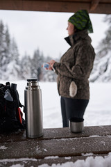 Young woman warming up with coffee during a winter hike