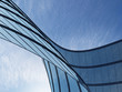 © nuchao - 3D stimulate of high rise curve glass building and dark steel window system on blue clear sky background,Business concept of future architecture,lookup to the angle of the corner building.