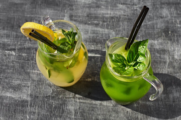 Lemonade with cucumbers, lemons and mint leafs in glasses on wooden table