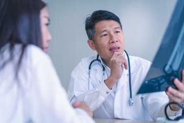 Man doctor points to x-ray film of woman patient.