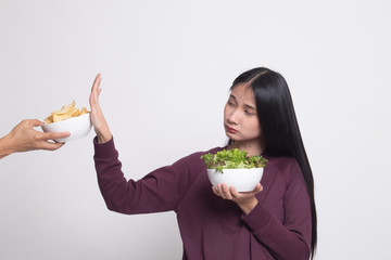 Young Asian woman with salad say no to potato chips.