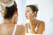 Leinwandbild Motiv Woman applying face cream in bathroom