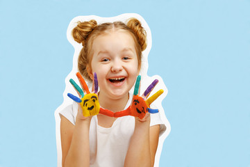 Cheerful little girl child shows hands painted with paint. Blue background, portrait