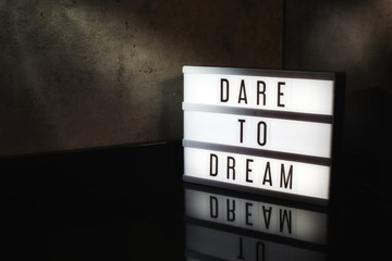 Dare to dream motivational message on a light box in a cinematic moody background