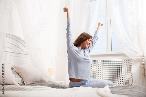 Happy Brunette Girl In The Light Blue Pajama Stretches Her