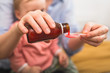© cherryandbees - close up of mother pouring cough syrup. blurred baby boy in background