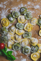 Wall Mural - Homemade fresh Italian ravioli pasta on wood table  with flour, basil,tomatoes,background,top view.