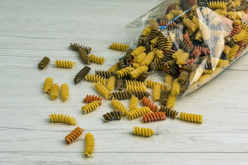 Wall Mural - Raw uncooked three-colored Fusilli  on white wood table.