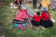 Several Peruvian women weaving a long striped textile