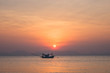 © terezika - Lonely fishing boat in the sea at sunset with a silhouette of mountains on the horizon