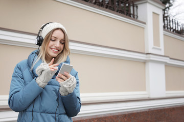 Poster - Young woman with headphones listening to music near light wall. Space for text