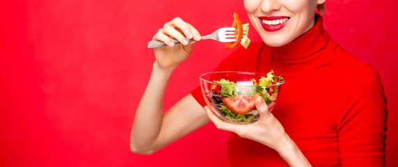 Beautiful caucasian woman eating salad over green natural background