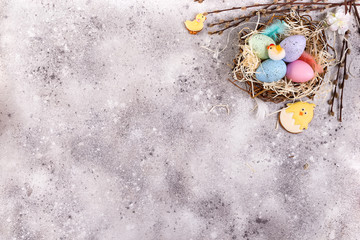 Wall Mural - Easter eggs in a nest of grass and homemade glazed cookies on a stone background, flat lay