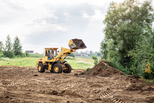 Large Yellow Wheel Loader Aligns A Piece Of Land For A New Building. May Be Cut To Banner Or Wallpaper With Copy Space.