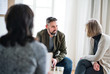 © Halfpoint - Man and women sitting in a circle during group therapy, talking.
