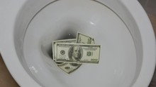 Hand Throws Dollars Into The Toilet (waste Of Money)