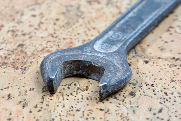 Old used wrench on a cork background. Vintage spanner