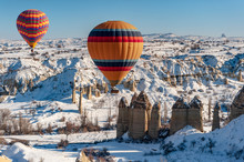 Colorful Balloon Over The Extraordinary Rocks Formations Rock Hills On Snowy Winter Of Cappadocia, Nevsehir,
